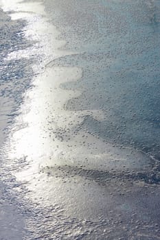 Fragment of frozen river surface with the rime as a randomly placed snowflakes