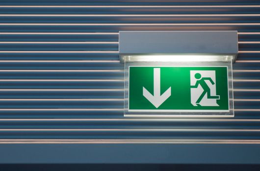 illuminated green emergency exit sign on a modern wall  