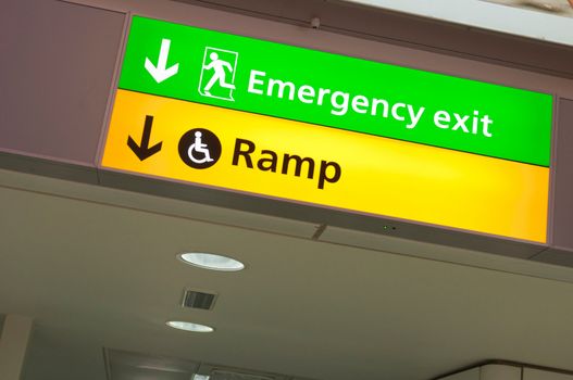 emergency exit and handicapped ramp sign at a international airport corridor