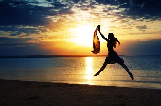 Jumping lady at the summer beach during sunset