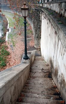 Urban scene with old stone staircase and street lamp near river