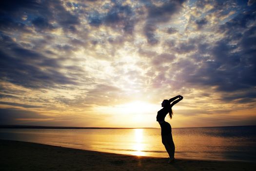 Lady making yoga exercise at the sea during sunset