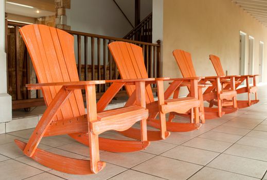 row of orange wooden rocking chairs on a porch (usual setting on a tropical resort)