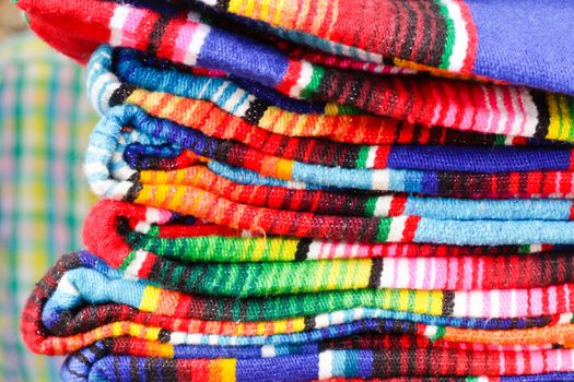 Pile of colorful mexican blankets for sale in a a market