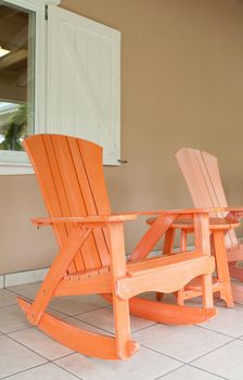 orange and pink wooden rocking chairs on a porch (usual setting on a tropical resort)