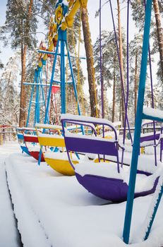 Child's swings in an empty park playground covered in snow.