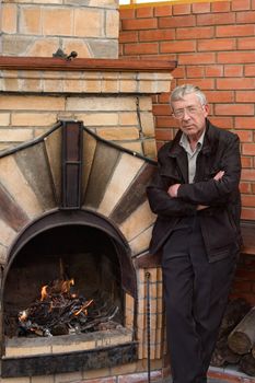 The man in glasses and a black jacket at a fireplace
