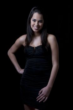 Young woman wearing a little black dress against a black background