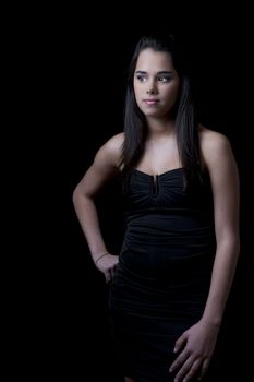 Young woman wearing a little black dress against a black background