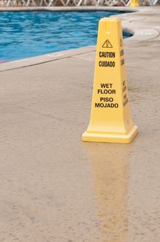 yellow caution sign regarding slippery surface next to a swimming pool (after a tropical storm)