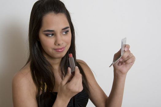 Young woman applying lipstick against a white background