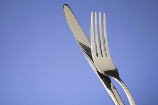 Single knife and fork isolated on a blue background
