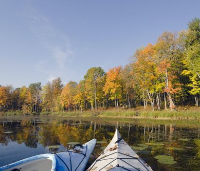 Two kayaks resting on the tranquil lake in autumn, with vibrant fall colors reflecting on the water