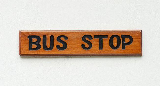 wooden bus stop sign on a white wall