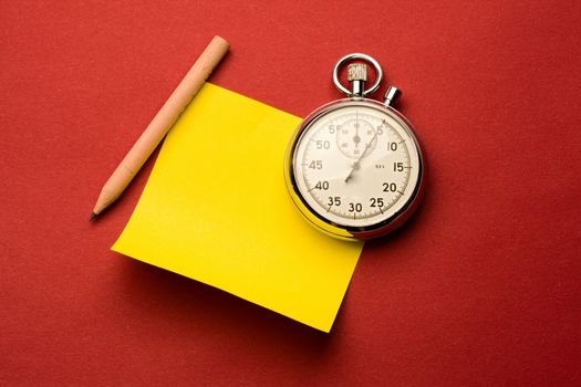 Stopwatch, pencil and label isolated on red