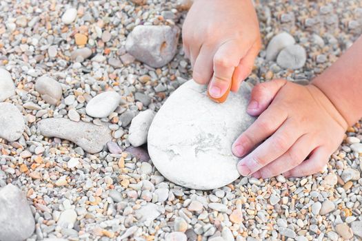 Close up of a young child's hands drawing on a stone