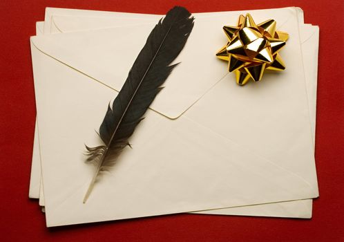 Envelope with ribbon and feather isolated on red background