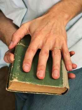 Man's hands hold the old green book