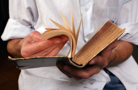 Man's hands hold the old green book