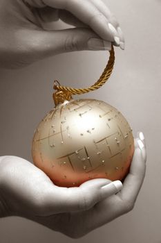 Gold sphere in female hands. Partial decolouration