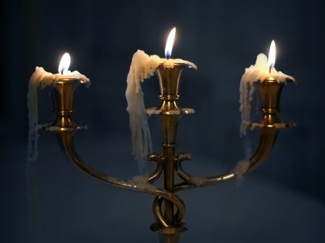 Three burning candles in an ancient gold candelabrum