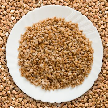 White plate with a buckwheat cereal against buckwheat