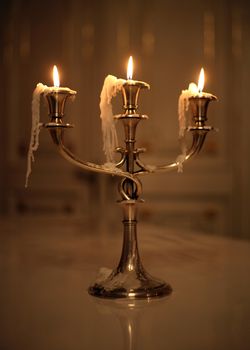 Three burning candles in an ancient gold candelabrum