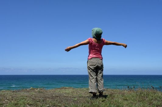 happy woman with arms wide open at the coast