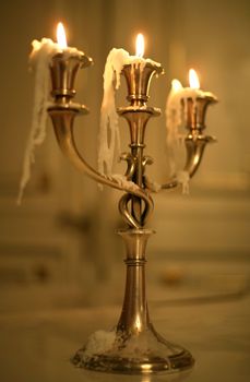 Three burning candles in an ancient gold candelabrum