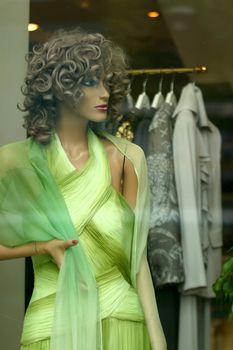 Doll in a green dress in a show-window of shop