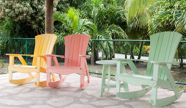 colorful wooden rocking chairs on a porch (setting on a tropical resort)