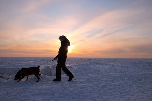 Men with rottweiler. Winter view to the beach. Beautiful sunset