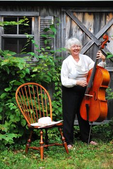 Female cellist standing with her cello outside.