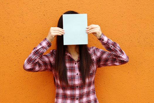 Asian woman using book to cover face