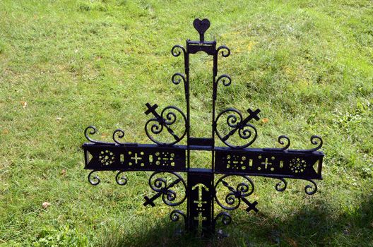 Metal decorative cross in meadow. Old Partisan cemetery.