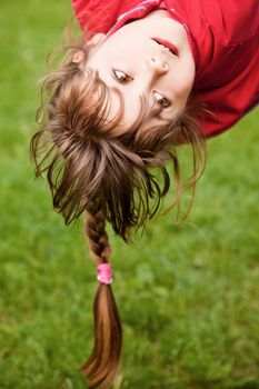 Sweet little girl with braid playing hanging upside-down