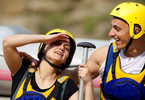 Happy couple with helmets and rafting equipment smiling