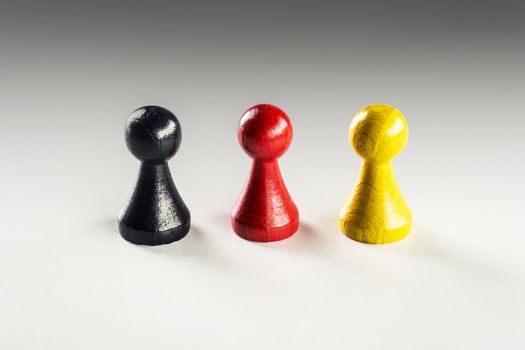 One black, one red and one yellow Ludo figure, the Germany flag colors