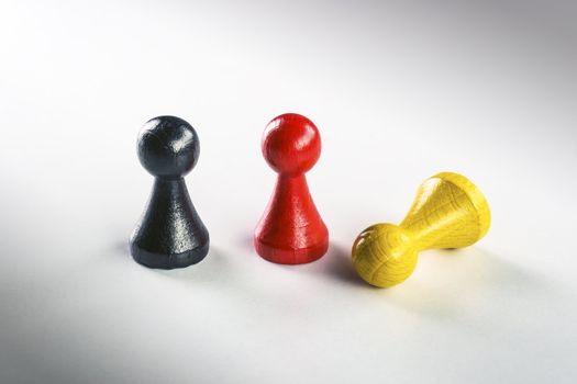 A standing black, red and a standing yellow lying Ludo figure