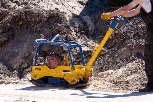 Worker at site Compacting a sand using a Plate Compactor