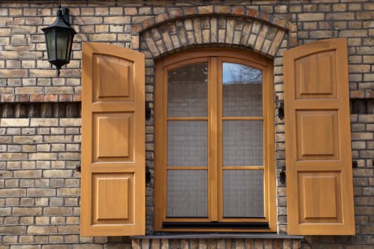 window in a brick wall with wooden shutters