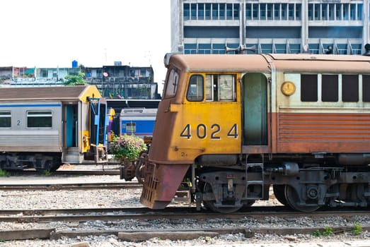 Old yellow diesel powered train moving away from train station
