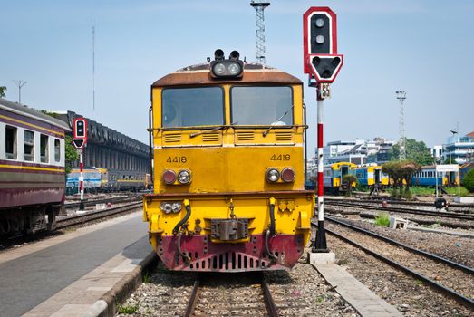 Old yellow diesel powered train moving away from train station

