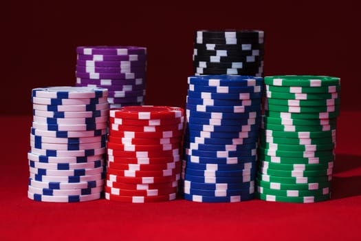 Stacks of Multicolored Poker Chips, closeup on red background