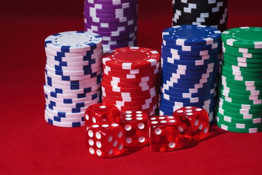 Stacks of Poker Chips with Playing Bones, closeup on red background