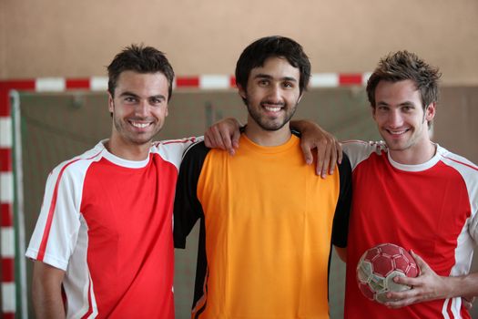 Three young men indoors with hand ball