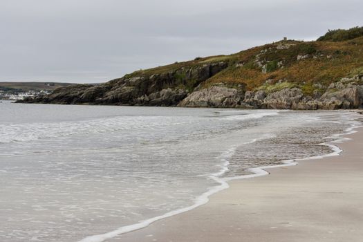 sandy coastline with hill in background. scotland, uk, europe