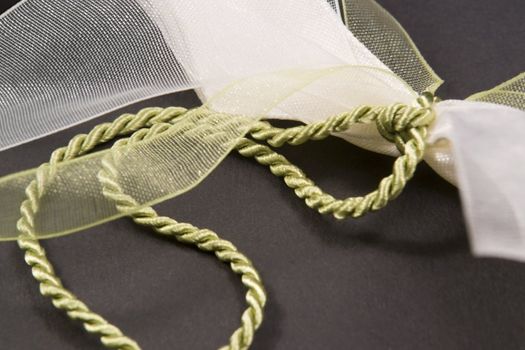 studio photography  of a decorative bow with green cord in dark back