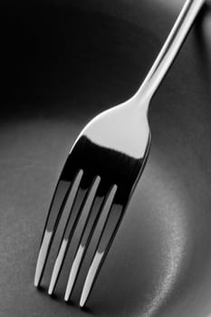 Black and White Stainless steel fork on ceramic bowl