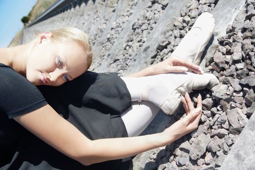 Tired woman sitting on the railway in ballet clothes